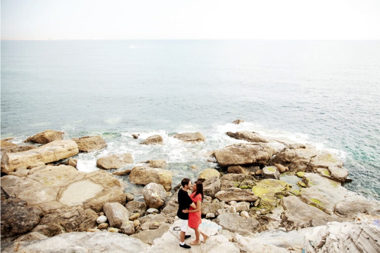 Wedding couple posing on the rocks with the sea in the background