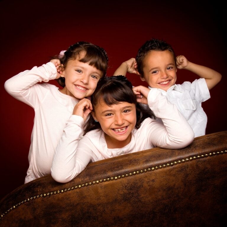 Three children posing with their hands over their ears